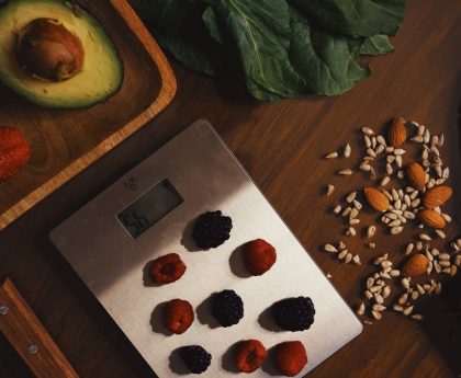 Top view of composed raw almond with seeds and avocado on table with berries on scales for cooking healthy dish